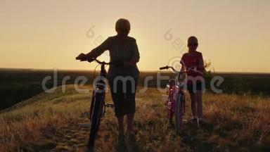 一位<strong>年迈</strong>的妇女正和孙女在农村散步。 他们走在旁边，开着自行车